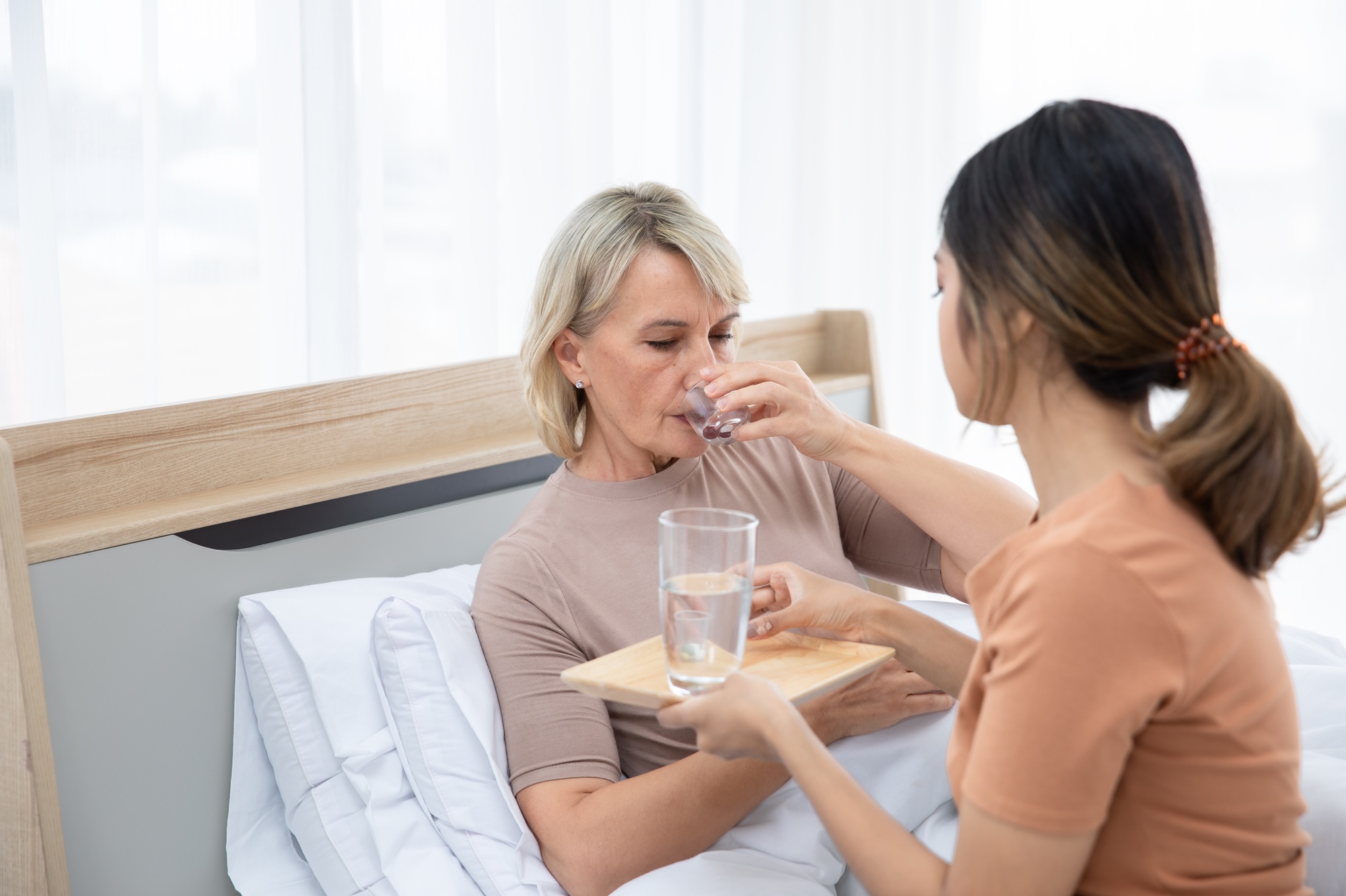 A caregiver administering medicines to elderly patients